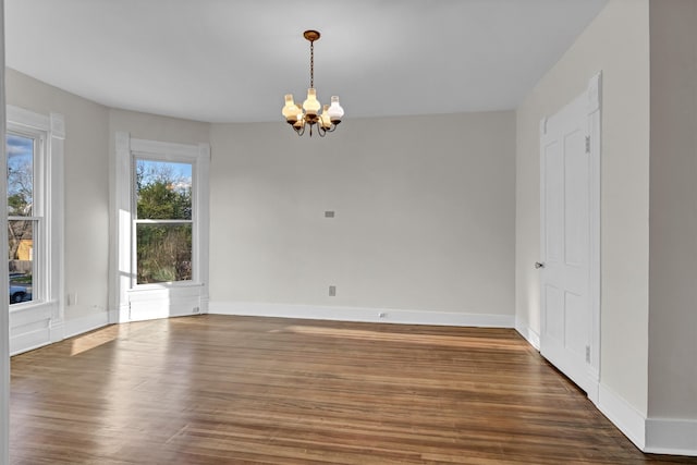 unfurnished room featuring a chandelier and dark hardwood / wood-style flooring