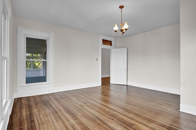 unfurnished room featuring a notable chandelier and dark hardwood / wood-style flooring