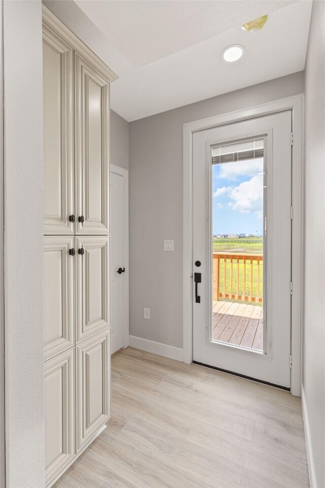 doorway featuring a textured ceiling and light hardwood / wood-style flooring