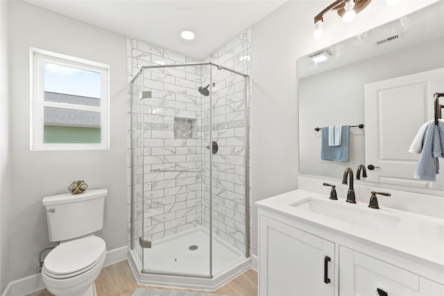 bathroom featuring wood-type flooring, vanity, a shower with shower door, and toilet