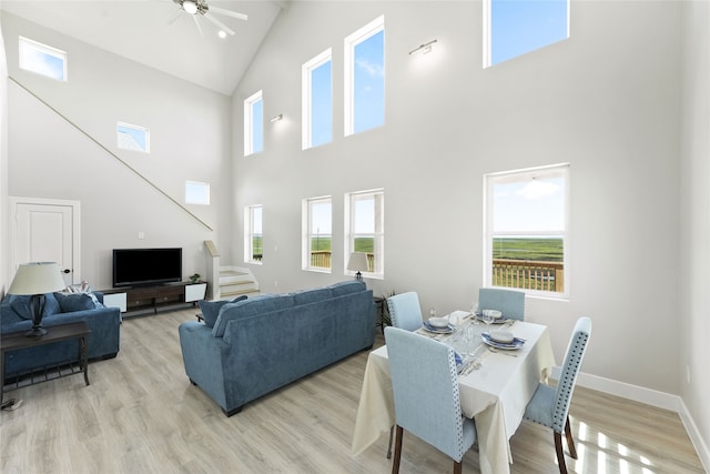 dining space featuring a high ceiling, light hardwood / wood-style floors, and ceiling fan