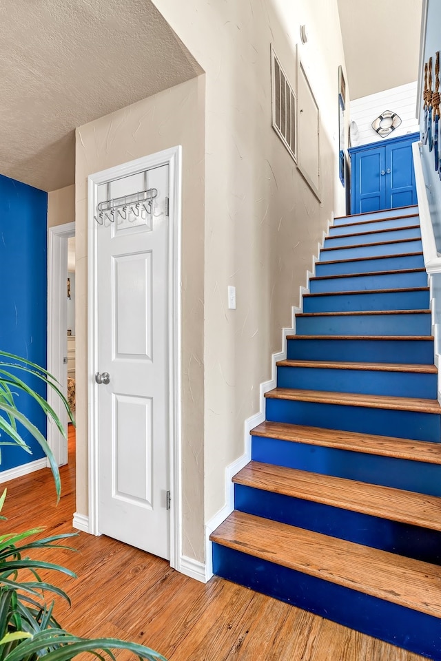 stairway featuring a textured ceiling and hardwood / wood-style flooring