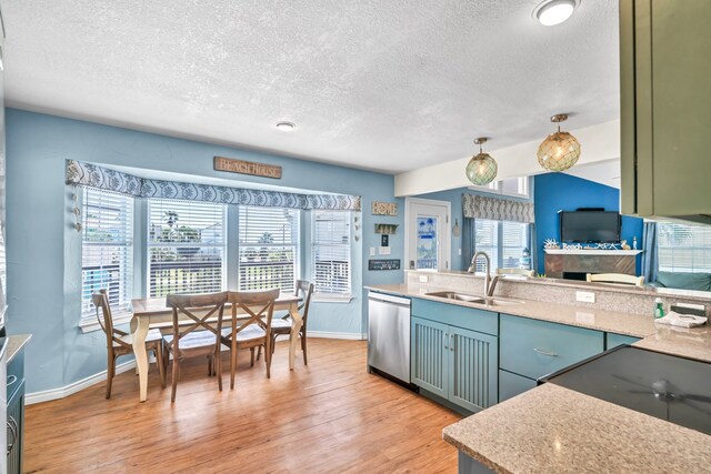 kitchen with hanging light fixtures, stainless steel dishwasher, sink, and light wood-type flooring