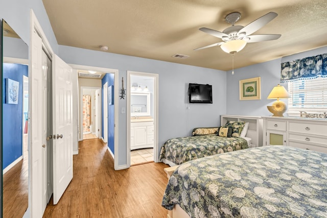 bedroom with connected bathroom, a textured ceiling, ceiling fan, and light hardwood / wood-style flooring