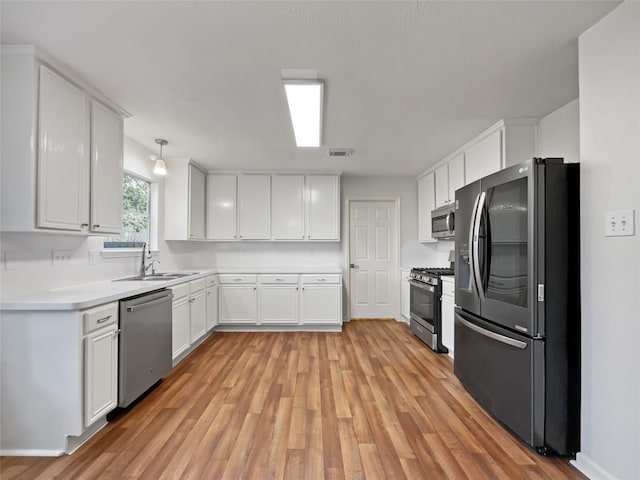 kitchen with white cabinets, light hardwood / wood-style flooring, appliances with stainless steel finishes, and sink