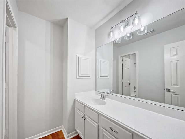 bathroom with hardwood / wood-style floors and vanity with extensive cabinet space