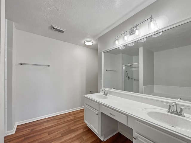 bathroom featuring a textured ceiling, dual sinks, hardwood / wood-style flooring, separate shower and tub, and oversized vanity