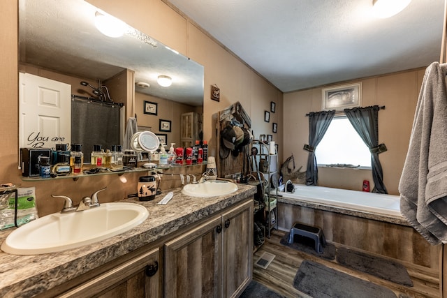 bathroom featuring hardwood / wood-style floors, a textured ceiling, a bath, and double sink vanity