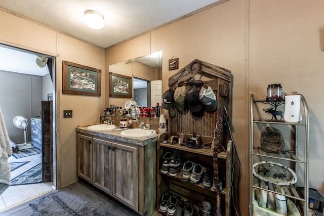 bathroom featuring dual sinks, a textured ceiling, tile floors, and vanity with extensive cabinet space