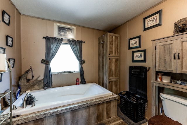 bathroom featuring toilet, a textured ceiling, and a tub