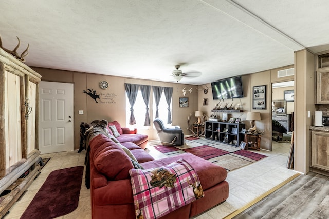 living room featuring light tile floors, a textured ceiling, and ceiling fan