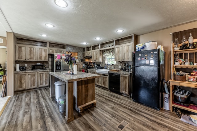 kitchen featuring a kitchen island, a textured ceiling, black appliances, and dark hardwood / wood-style flooring