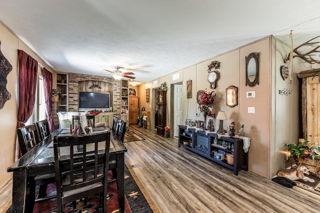 dining space with a textured ceiling, brick wall, ceiling fan, and light hardwood / wood-style flooring