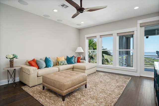 living room featuring dark hardwood / wood-style floors, a water view, and ceiling fan