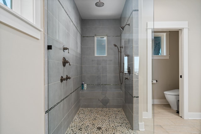 bathroom with toilet, tile floors, and tiled shower