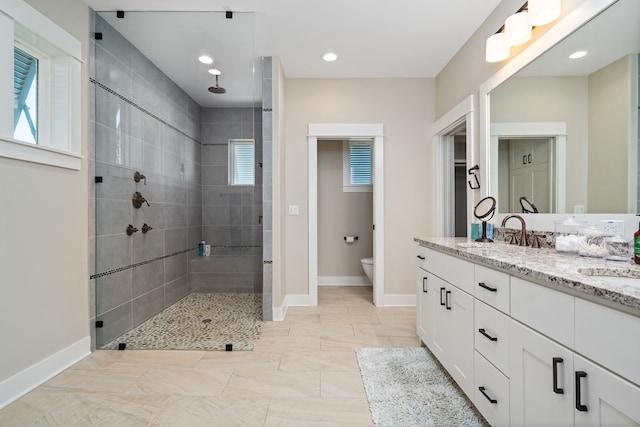 bathroom featuring tile floors, tiled shower, toilet, and vanity