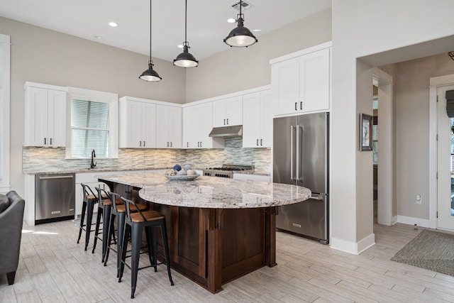 kitchen with appliances with stainless steel finishes, light stone countertops, backsplash, and a center island