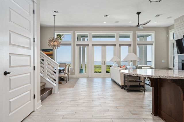 interior space with light stone countertops, hanging light fixtures, ceiling fan with notable chandelier, and a healthy amount of sunlight