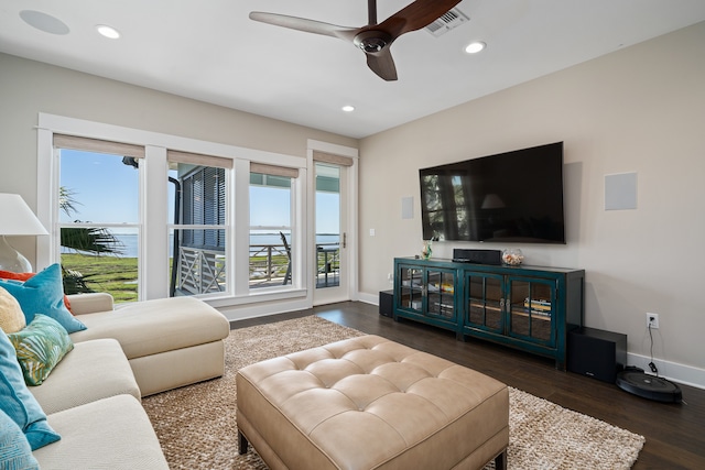 living room with ceiling fan, a water view, and dark wood-type flooring