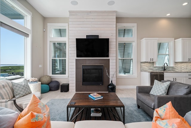 carpeted living room with a healthy amount of sunlight, sink, and a tile fireplace