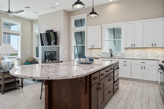 kitchen featuring tasteful backsplash, hanging light fixtures, ceiling fan, and white cabinets