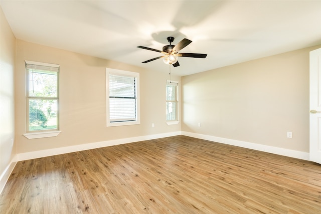 empty room with ceiling fan, a wealth of natural light, and light wood-type flooring