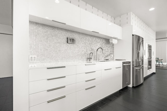 kitchen with stainless steel appliances, white cabinets, dark hardwood / wood-style floors, sink, and tasteful backsplash