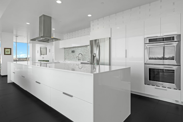 kitchen with stainless steel appliances, island range hood, tasteful backsplash, a center island, and white cabinets