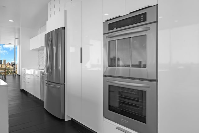 kitchen with stainless steel appliances, white cabinets, and dark wood-type flooring