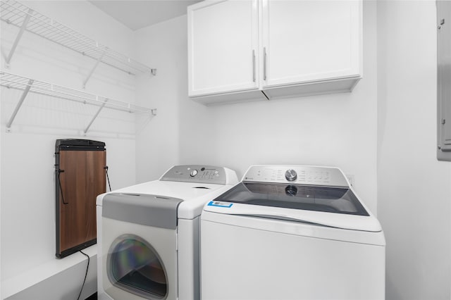 clothes washing area with washer and dryer and cabinets