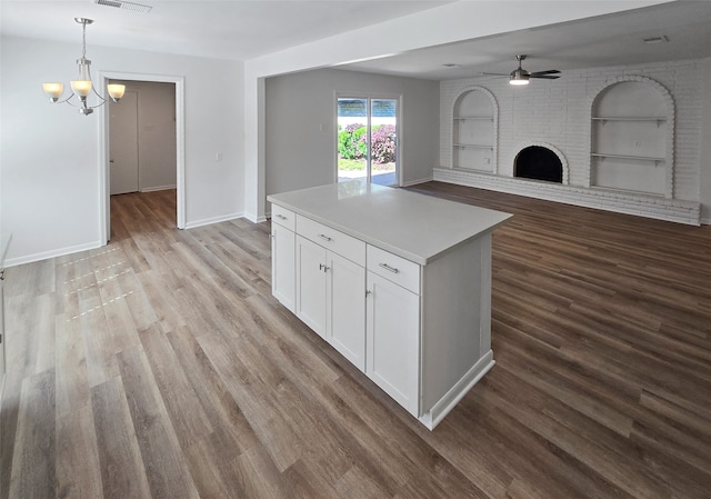 kitchen featuring ceiling fan with notable chandelier, light hardwood / wood-style flooring, built in shelves, a brick fireplace, and white cabinetry