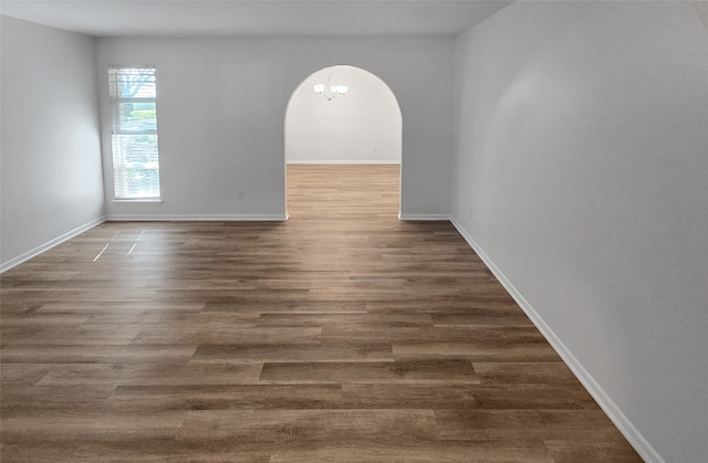 spare room with dark wood-type flooring and a chandelier