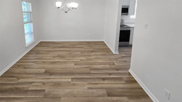 unfurnished room featuring light wood-type flooring and an inviting chandelier