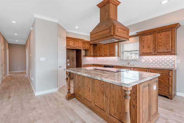 kitchen featuring a center island, premium range hood, light hardwood / wood-style flooring, backsplash, and light stone counters