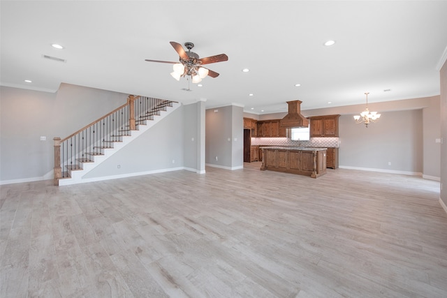 unfurnished living room with light wood-type flooring, crown molding, and ceiling fan with notable chandelier