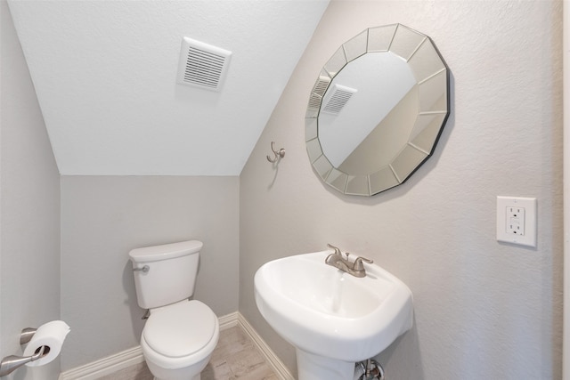 bathroom with hardwood / wood-style floors, sink, vaulted ceiling, and toilet