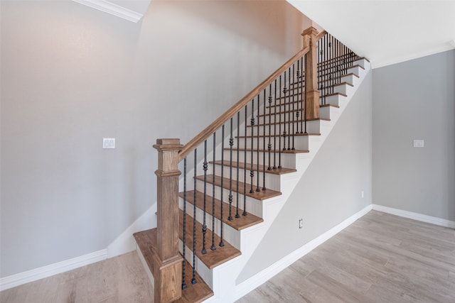 staircase with light hardwood / wood-style floors and crown molding