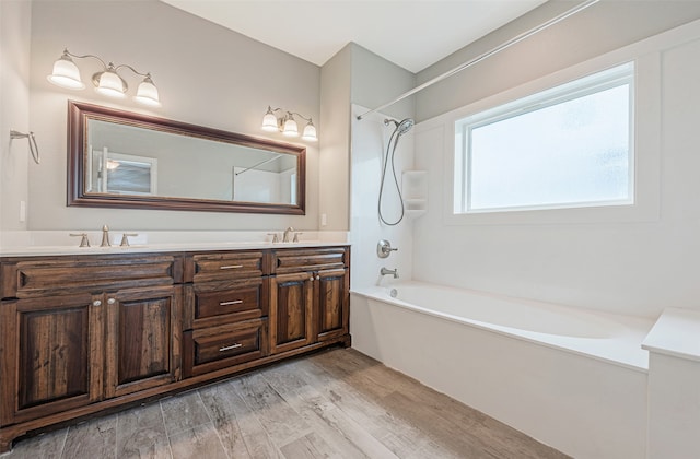 bathroom with shower / bath combination, vanity with extensive cabinet space, hardwood / wood-style flooring, and double sink