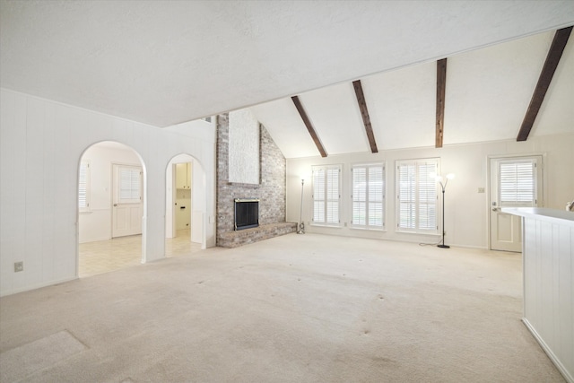 unfurnished living room featuring light carpet, a large fireplace, and vaulted ceiling with beams