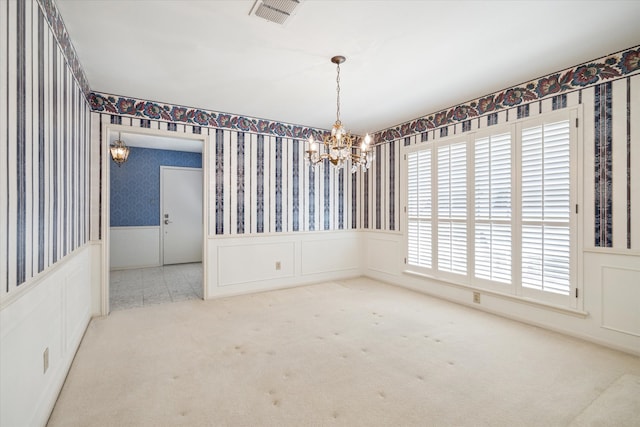 carpeted empty room with a chandelier