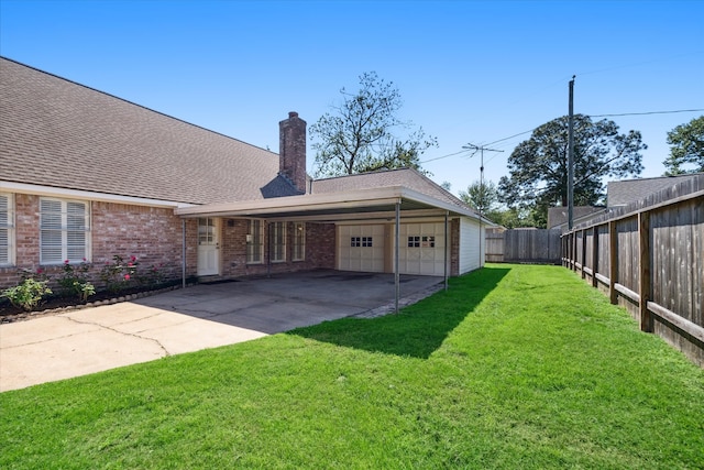 back of house featuring a carport, a lawn, and a garage