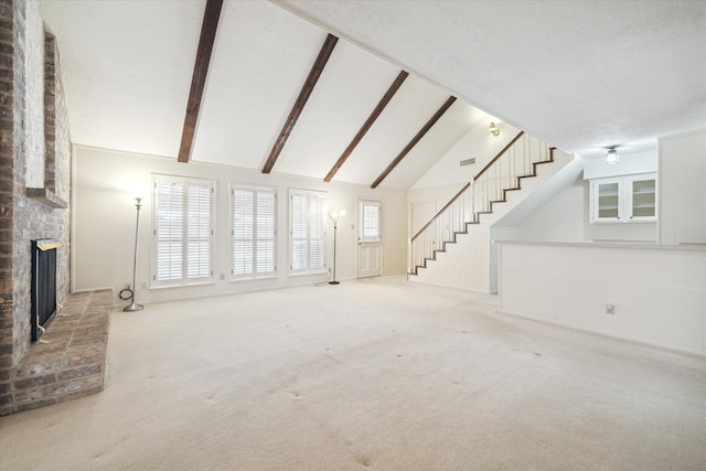 unfurnished living room with brick wall, a brick fireplace, light colored carpet, and vaulted ceiling with beams