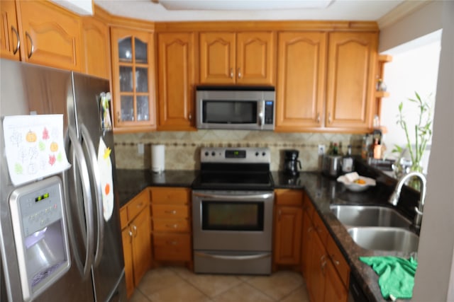 kitchen with backsplash, appliances with stainless steel finishes, light tile floors, and sink