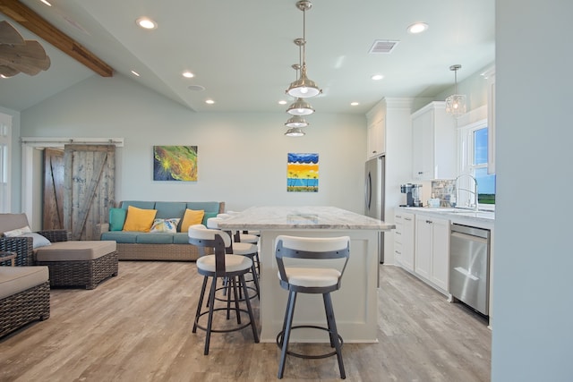 kitchen with white cabinets, light hardwood / wood-style flooring, a center island, and stainless steel appliances