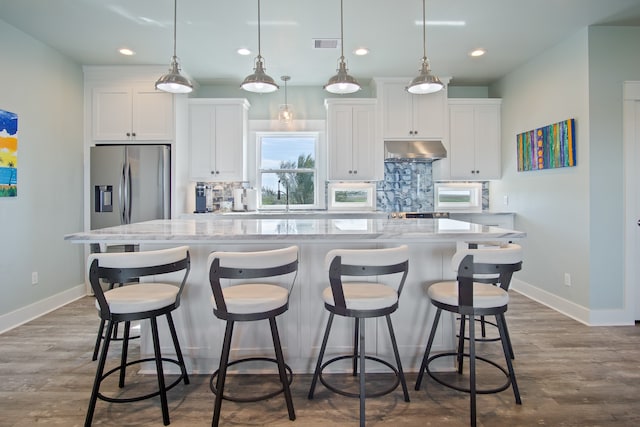 kitchen featuring tasteful backsplash, hardwood / wood-style floors, a center island with sink, and hanging light fixtures