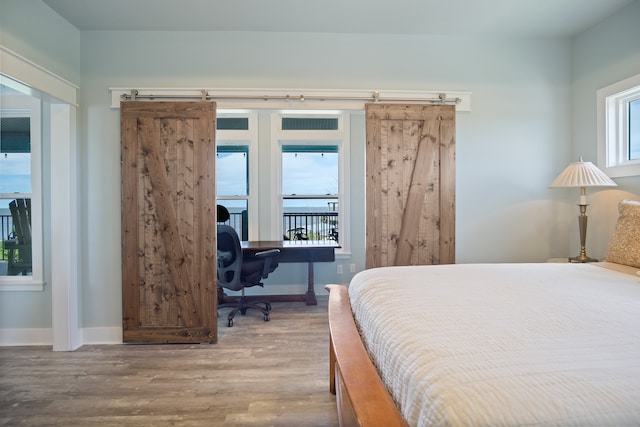 bedroom with a barn door, access to exterior, and light hardwood / wood-style floors