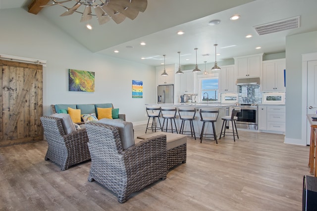 living room with sink, ceiling fan, light hardwood / wood-style floors, high vaulted ceiling, and beam ceiling