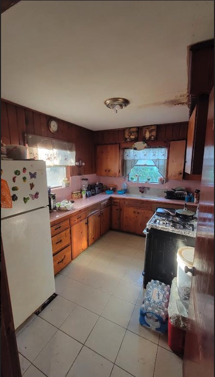 kitchen featuring stove, white refrigerator, and light tile flooring