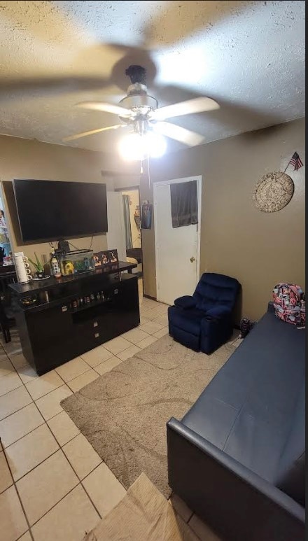 tiled bedroom featuring ceiling fan and a textured ceiling