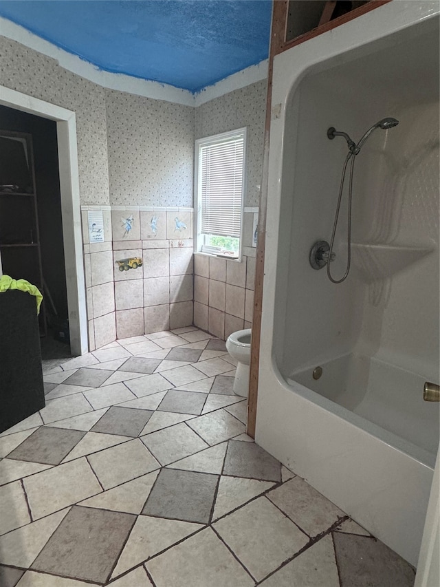 bathroom with tile patterned flooring, tiled shower / bath combo, and toilet